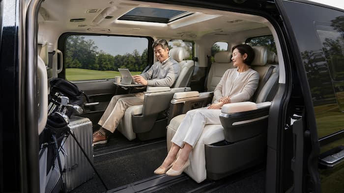 고급 MPV 실내에서 장거리 이동과 휴식을 즐기는 중장년 승객 이미지