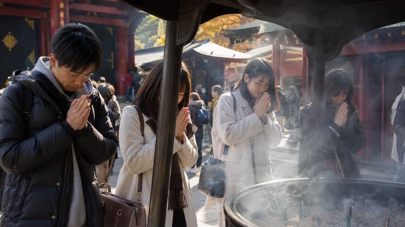 일본 신사에서 향 연기 속에 기도하는 젊은 일본인들