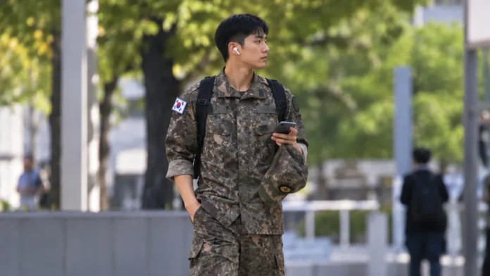 featured-street-soldier-head-safe-16x9 이어폰을 끼고 군모와 스마트폰을 손에 든 채 도심을 걷는 군복 차림 장병의 모습