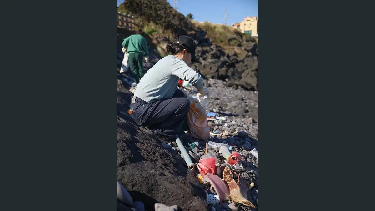 제주 해안의 바위와 자갈 사이에서 쓰레기를 수거하는 플라스틱 제로 제주 원정대 참가자