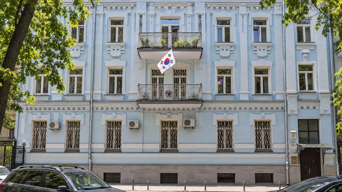 주우크라이나 대한민국 대사관의 옅은 청색 외벽과 중앙 발코니, 태극기를 정면에서 본 재구성 이미지